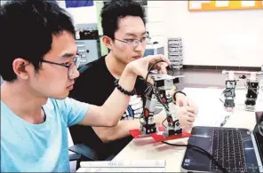  ?? LIU YING / XINHUA ?? Two college students from the University of Shanghai for Science and Technology work on the prototype of a robot.