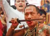  ??  ?? An Indonesian man believed to be in a trance cuts his own tongue with a daggar while his cheek is pierced with a needle, at a temple in Jakarta to mark the Cap Go Meh Festival.