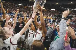  ?? AP PHOTO BY MIC SMITH ?? South Carolina star Aliyah Boston holds up the SEC tournament trophy after the Gamecocks beat Tennessee on March 5 in Greenville, S.C.