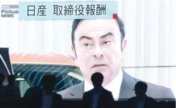  ?? — AFP ?? People walk past a screen showing a news programme featuring Nissan Chairman Carlos Ghosn in Tokyo.