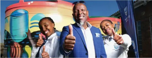  ?? Photo: supplied ?? Khutliso Daniels Secondary School Principal Radio Ncube celebrates the donation of eye-catching water tanks with two of the school's learners.