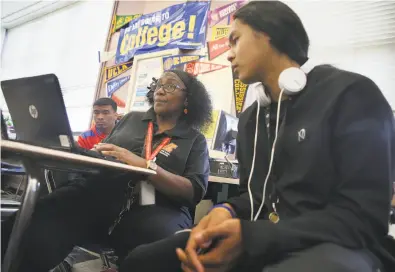  ?? Photos by Liz Hafalia / The Chronicle ?? Top: Senior Andy Kim ( right) gets his biography checked by LuPaulette Taylor during an English class at McClymonds High School.