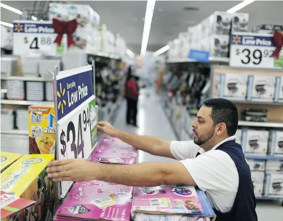  ?? JOE RAEDLE / GETTY IMAGES ?? A worker fixes a display at a Walmart store in Miami. Retail companies across the U. S. have voiced their concerns about a borderadju­stment tax plan, which they say will raise the price of imported goods.