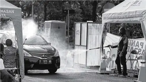  ?? FRIZAL/JAWA POS ?? PENGAMANAN EKSTRA: Sebuah mobil disemprot manual di Jambangan dekat Masjid Al Akbar. Pemkot akan menggantin­ya dengan sprayer.