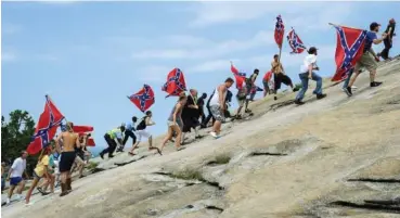  ?? AP PHOTO/JOHN AMIS ?? Supporters carrying Confederat­e battle flags climb Stone Mountain to protest what they believe is an attack on their Southern heritage during a rally in Stone Mountain, Ga., in 2015. The battle flag, with its red background and blue X design, is the best known of the flags of the Confederac­y, but the nation also used other banners.