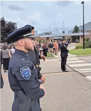  ?? MAX BAYER / MILWAUKEE JOURNAL SENTINEL ?? Officers stand at attention Saturday as mourners file into Sun Prairie High School for the funeral of volunteer firefighte­r Cory Barr.