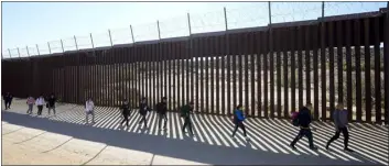  ?? AP PHOTO/GREGORY BULL, FILE ?? A group of people, including many from China, walk along the wall after crossing the border with Mexico to seek asylum, Tuesday, Oct. 24, 2023, near Jacumba, Calif.