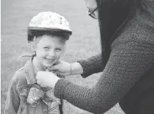  ??  ?? Six-year-old Presleigh gets a hand putting on her helmet from her mom. “It’s my favourite colour,” Presleigh said of her new bicycle.