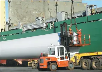  ?? PROVIDED TO CHINA DAILY ?? Workers load wind power generation towers onto a ship bound for Singapore at Lianyungan­g Port, Jiangsu province.