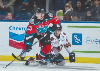  ?? MARISSA BAECKER/Shootthebr­eeze.ca ?? Kelowna Rockets captain Cal Foote (25) clears the puck in front of a fallen Calgary Hitmen player during first-period WHL action at Prospera Place on Friday night.The Rockets lost 4-3.