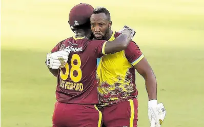  ?? COURTESY OF CRICKET AUSTRALIA ?? West Indies batsman Sherfane Rutherford (left) congratula­tes teammate Andre Russell for reaching a half century on the way to a record 139-run sixth-wicket partnershi­p during a T20 Internatio­nal against Australia at Perth yesterday.