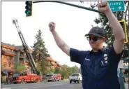  ?? (AP/Bay Area News Group/Jane Tyska) ?? South Lake Tahoe firefighte­r Leo Gebhardt gestures to passing cars on Sunday as they honk their horns along Highway 50 near Stateline, Nev., in South Lake Tahoe, Calif. Fire officials downgraded some evacuation orders near Lake Tahoe and allowed thousands of South Lake Tahoe residents who fled the Caldor Fire last week to return home Sunday.