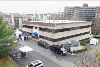  ?? Tyler Sizemore / Hearst Connecticu­t Media ?? At top, a Stamford resident moves an old car that is part of the movie set where “The Good Nurse” is being filmed in Stamford on Thursday. Above, tents are set up in the parking lot of the movie set.