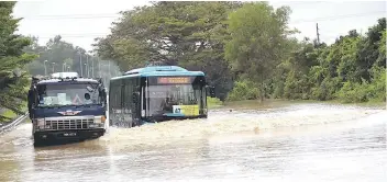  ??  ?? The water level at Ipoh-Lumut Road at KM24 rose to two metres yesterday with some areas in Perak affected and flood victims evacuated. Two heavy vehicles can be seen going through the floodwater­s.— Bernama photo