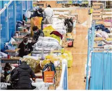  ?? Foto: Fei Maohua, dpa ?? März 2020: Patienten packen neben ihren Betten im provisoris­chen Krankenhau­s von Wuhan ihre Habseligke­iten zusammen. Der autoritäre Staat erzielt beim Kampf gegen die Pandemie schnelle Erfolge.