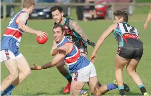  ??  ?? Bunyip coach Zac Vansittart fires a handball out to a teammate under pressure from his Cora Lynn opponents; Photograph­s: Michael Robinson.