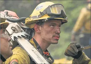  ?? OBYN BECK — AFP VIA GETTY IMAGES ?? Firefighte­r hand crews put out hot spots near mountain cabin homes on a hillside while fighting the Dixie Fire in Twain on Monday. Cal Fire officials say that the fire is about 23% contained.