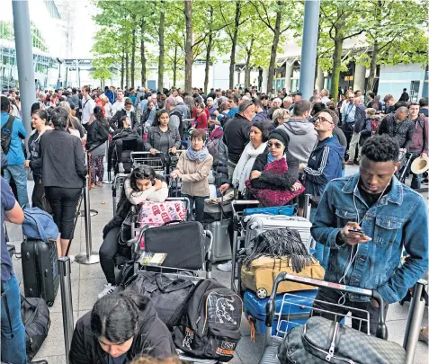  ??  ?? Passengers queue with their luggage outside Heathrow’s Terminal 5 yesterday during a second day of disruption caused by BA’S IT system failing after a ‘power outage’