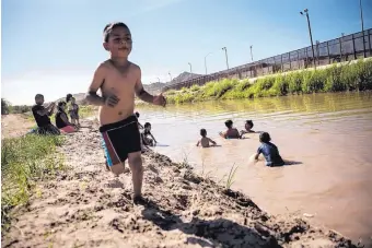  ?? ROBERTO E. ROSALES/JOURNAL ?? Families from the Ciudad Juárez neighborho­od of Anapra play in the Rio Grande near the border fence dividing the United States and Mexico.