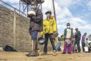  ??  ?? Children line up for porridge in Harare, Zimbabwe, Dec. 31, 2020.