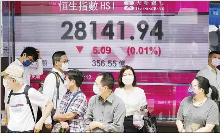  ??  ?? People wearing face masks walk past a bank’s electronic board showing the Hong Kong share index in Hong Kong, Tuesday, July 6, 2021. Asian shares were mixed in muted trading on Tuesday as oil prices surged higher after a meeting of oil producing nations was postponed. (AP)