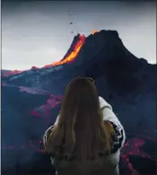  ?? MARCO DI MARCO — THE ASSOCIATED PRESS ?? A woman takes a photo as lava flows from an eruption of a volcano on the Reykjanes Peninsula in southweste­rn Iceland on Tuesday. Iceland’s latest volcano eruption is quickly attracting crowds of people to the lava flows.