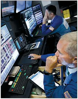  ?? AP/RICHARD DREW ?? Trader Timothy Nick (foreground) works on the floor of the New York Stock Exchange.