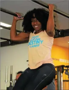  ??  ?? Fabienne Daniel pulls herself up and down using arm strength at the I Am Fit Studio in Sinking Spring. The fitness gym teaches their clients that nutrition, cardio and strength training are the way to lose weight.