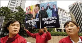  ?? AHN YOUNG-JOON / ASSOCIATED PRESS ?? An activist holds a banner of photos of North Korean leader Kim Jong Un with President Donald Trump and South Korean President Moon Jae-in at a rally for peace Tuesday in front of the Singapore Embassy in Seoul, South Korea.