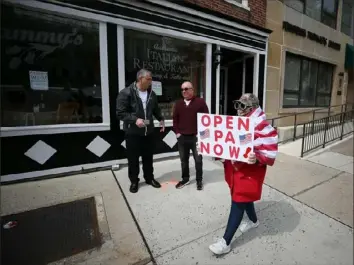  ?? David Maialetti/Philadelph­ia Inquirer ?? A protester walks by a restaurant open for takeout only on April 20 as protesters gathered outside the Capital Complex in Harrisburg to demand that Gov. Tom Wolf lift COVID-19 restrictio­ns on businesses in the state.