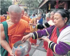  ??  ?? Highland people clad in traditiona­l attire offer alms to monks.