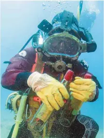  ?? BORIS HORVAT AGENCE FRANCE-PRESSE ?? Un plongeur montre des bouteilles repérées dans un cellier en mer Méditerran­ée. L’expérience vise à évaluer les effets de la maturation des vins de Bandol enfouis sous l’eau pendant un an.