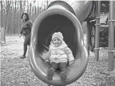  ?? ?? Aria Johnson, 2, smiles as she comes down from a tunnel slide as her mother Ashley Johnson watches at Bauervic Woods Park in Southfield.