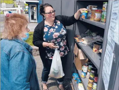  ?? BRAD HORRIGAN/HARTFORD COURANT ?? Sarah Toomey, right, helps Elaine Pollack select food Saturday morning from the “Little Free Pantry” outside Northwest CT Realty in Winsted.