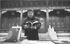  ?? ZOU HONG / CHINA DAILY ?? Shan Jixiang, the director of the Palace Museum in Beijing, shows a recent cultural creativity product of the museum, a book for readers to solve puzzles with online interactio­n.