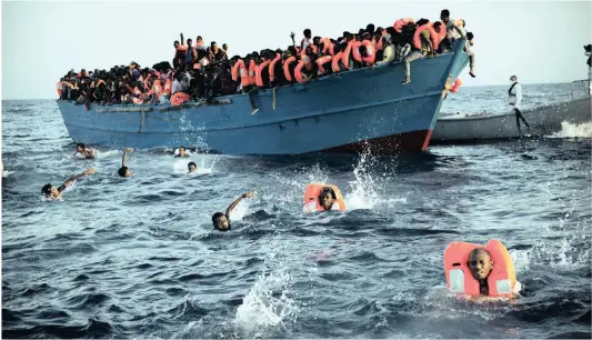  ?? Picture: AP ?? Migrants, most of them from Eritrea, jump into the water from a crowded wooden boat as they are helped by members of an NGO during a rescue operation at the Mediterran­ean sea, about 24km north of Sabratha, Libya, on Monday. Thousands of migrants and...