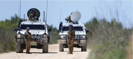  ?? (Reuters) ?? UN PEACEKEEPE­RS of the United Nations Interim Force in Lebanon (UNIFIL) stand near their vehicles in the Lebanese village of Labbouneh near the Lebanese-Israeli border, earlier this year.