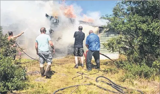  ?? SUBMITTED PHOTOS BY CASEY HUSK EVANS ?? Residents and cottagers on the Witless Bay Line fight a cabin fire last Saturday.