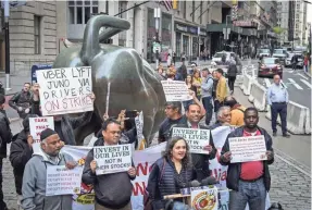  ?? DREW ANGERER/GETTY IMAGES ?? A group of independen­t drivers and supporters protest Uber and other app-based ride-hailing companies near the Wall Street Charging Bull statue on Wednesday in New York City.