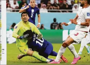 ?? Manu Fernandez / Associated Press ?? Christian Pulisic of the United States, center, collides with Iran’s goalkeeper Alireza Beiranvand, left, after scoring his sides first goal during the World Cup group B soccer match Tuesday at the Al Thumama Stadium in Doha, Qatar.