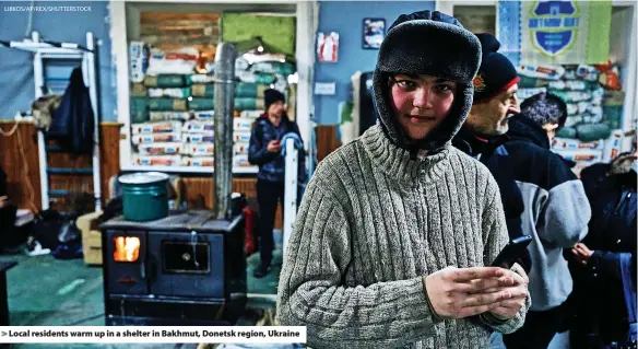  ?? LIBKOS/AP/REX/SHUTTERSTO­CK ?? > Local residents warm up in a shelter in Bakhmut, Donetsk region, Ukraine