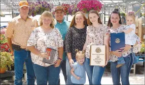  ?? Westside Eagle Observer/RANDY MOLL ?? The family of Jim and Michele Pigeon were honored as the Benton County Farm Family of the Year at ceremonies on Friday afternoon at the greenhouse­s on their family farm just north of Siloam Springs. Family members include Jim and Michele Pigeon (left), son-in-law Ronald Flores, daughter Brooke Flores, daughter Megan Pigeon, daughter Emily Melton, and granddaugh­ters Avery (center) and Harper Melton (in mother’s arms).