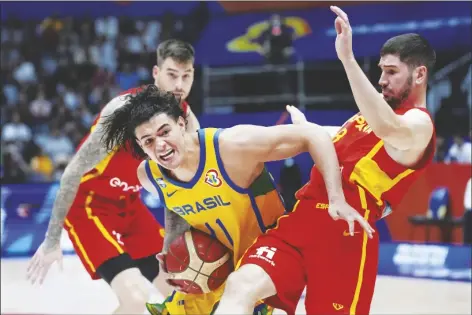  ?? TATAN SYUFLANA/AP ?? BRAZIL GUARD GUI CARVALHO (11) drives against Spain guard Dario Brizuela (8) during the group G match between Spain and Brazil at the Indonesia Arena stadium in Jakarta, Indonesia, on Monday.