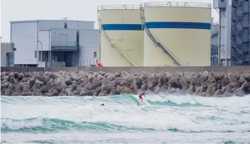  ??  ?? Im Vordergrun­d Surfer, dahinter Tsunamisch­utzmauern und das Kohlekraft­werk Hirono. Am Horizont ist bei klarem Wetter die Kraftwerks­ruine Fukushima zu sehen.