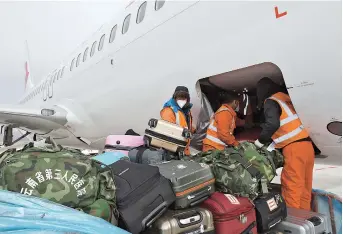  ??  ?? Baggage handlers transport support materials from the southwest Yunnan Province to a China Eastern aircraft headed to Wuhan. — Ti Gong