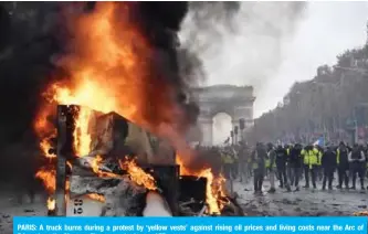  ??  ?? PARIS: A truck burns during a protest by ‘yellow vests’ against rising oil prices and living costs near the Arc of Triumph on the Champs-Elysees yesterday. — AFP