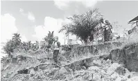  ??  ?? PERIKSA: Anggota APM memantau perkembang­an tanah runtuh di tebing sungai berdekatan di Rumah Sara di Sungai Telungan, Tinjar.