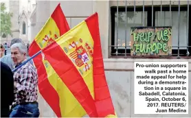  ??  ?? Pro-union supporters walk past a home made appeal for help during a demonstrat­ion in a square in Sabadell, Calatonia, Spain, October 6, 2017. REUTERS/ Juan Medina