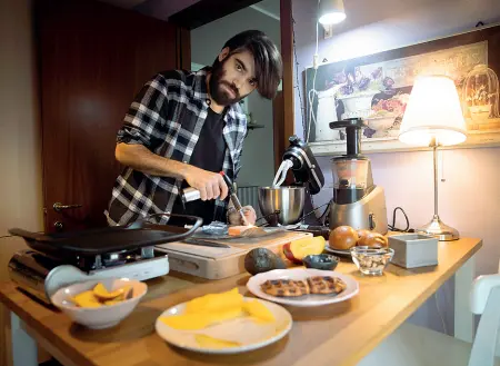  ??  ?? Lorenzo Bigiarelli nella sua casa a Milano col cellulare su una pagina di Instagram, davanti a due piccoli specchi, fotografat­o dal suo balcone sotto la casa e in cucina mentre prepara il finger food usato nella foto di copertina