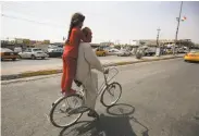  ?? Ahmad Al-rubaye / AFP / Getty Images ?? A man and a girl ride a bicycle in the Kurdish city of Kirkuk, Iraq, after a curfew was partly lifted.